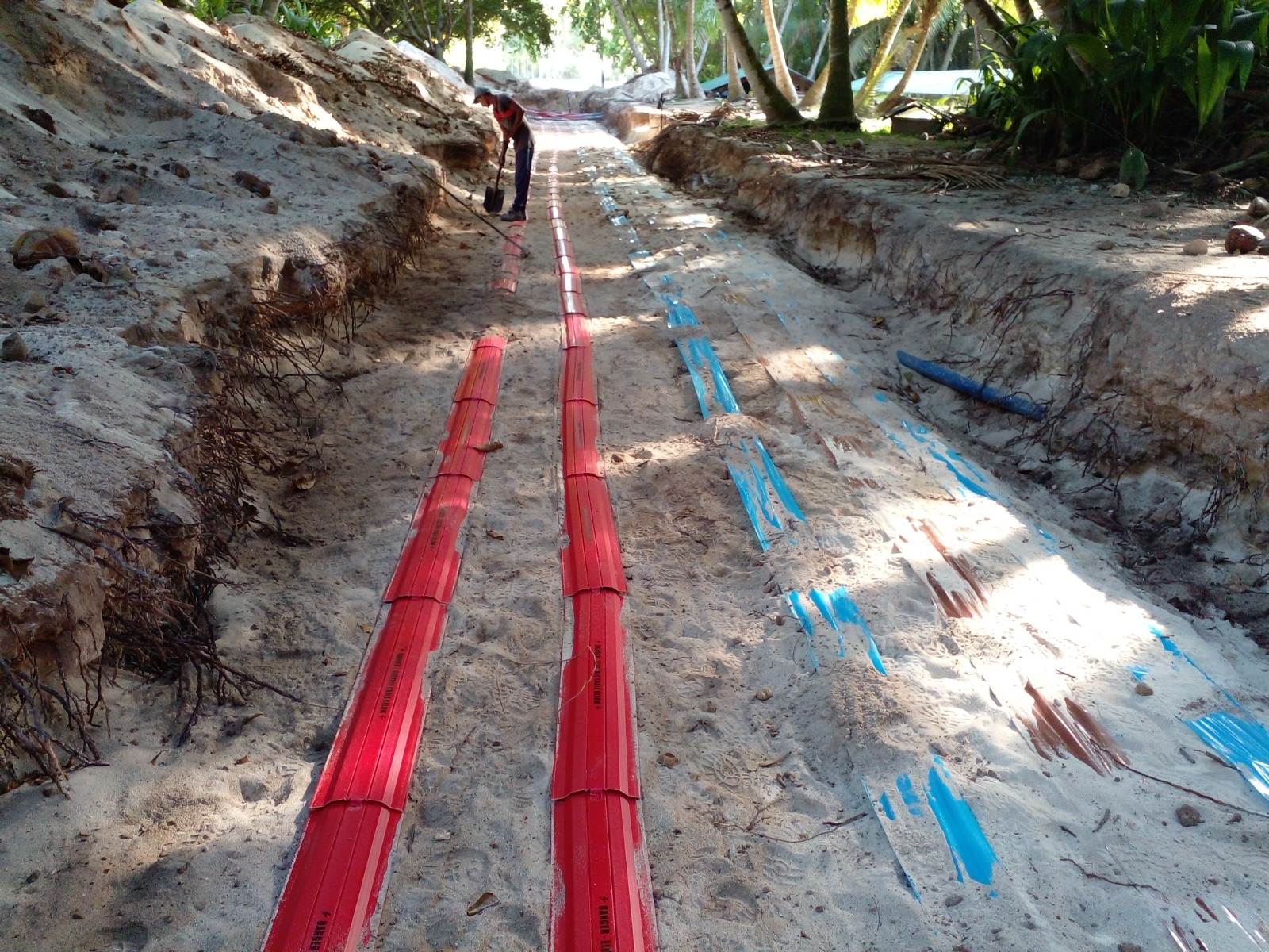 Buried LV cabling protected with DANGER ELECTRIC CABLE cover tiles, inspected before backfill
