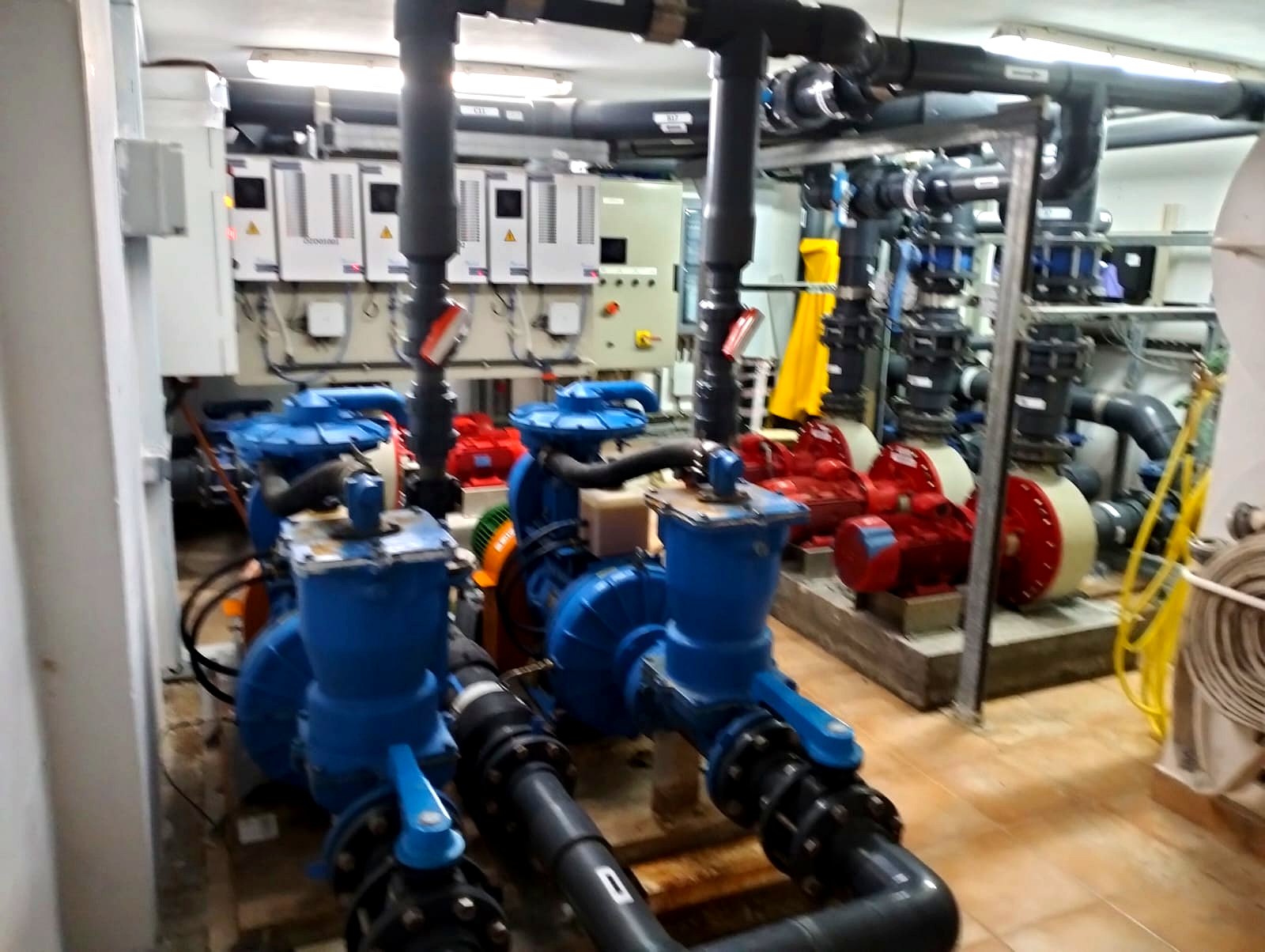 Combined plant room — pool circulation pumps with strainer pots and variable-speed drives, fire pump set beyond