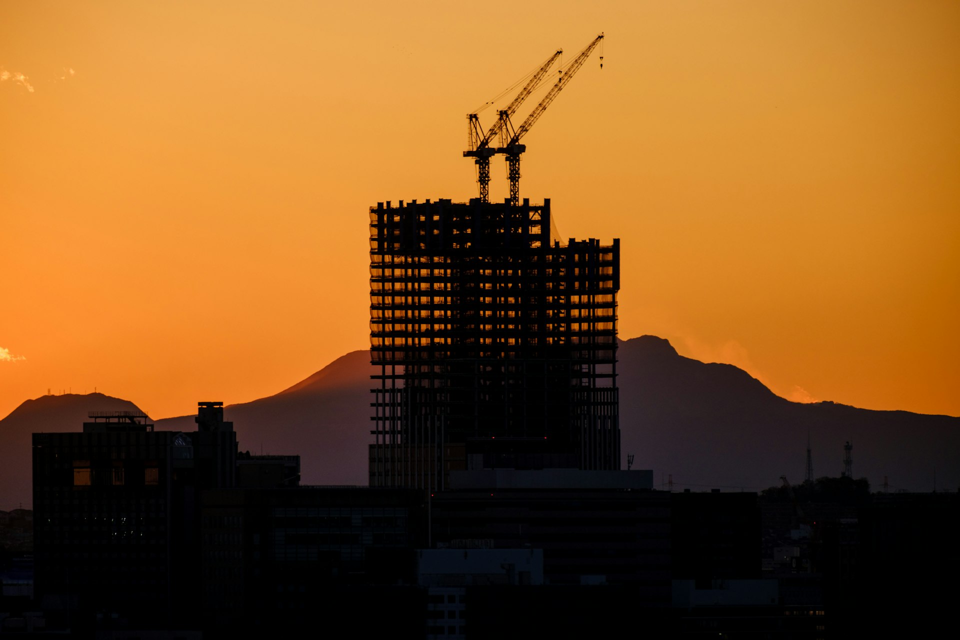 High-rise construction programme progressing beneath tower cranes at dusk