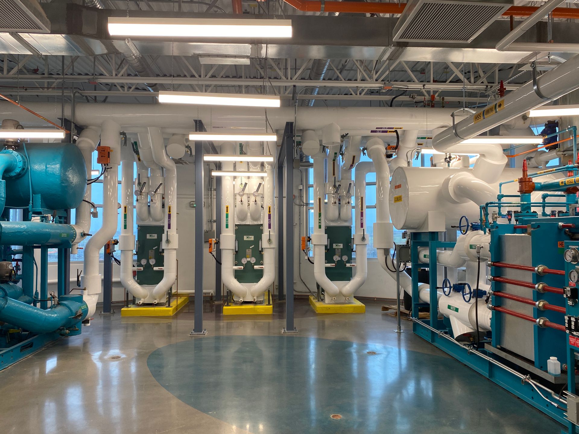 Modern mechanical plant room with insulated white pipework, heat exchangers and chiller plant
